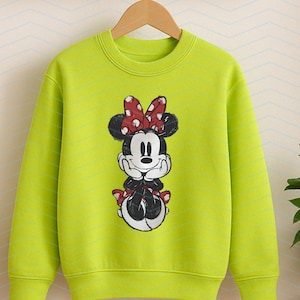 May include: A lime green sweatshirt featuring a graphic of Minnie Mouse. Minnie Mouse is depicted in black and white with a red polka dot bow and matching accents. The sweatshirt has a crew neck and long sleeves, suitable for children.