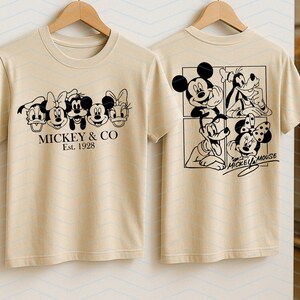 May include: A beige t-shirt featuring a black graphic print of Disney characters on the front and back. The front displays five character faces with the text MICKEY & CO Est. 1928. The back shows four characters in a grid with the text MICKEY MOUSE.