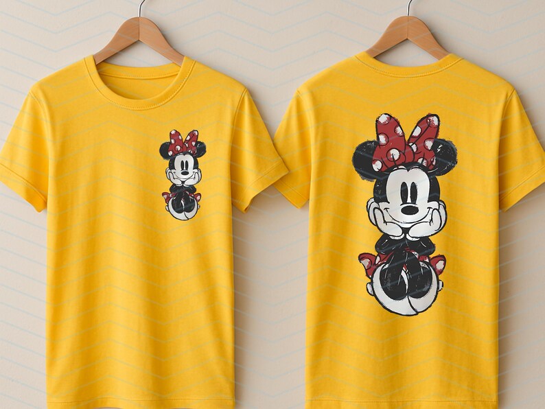 May include: Two yellow t-shirts with a Minnie Mouse graphic. One shirt has a small graphic on the front, the other has a large graphic on the back. The Minnie Mouse design features a red bow with white polka dots.