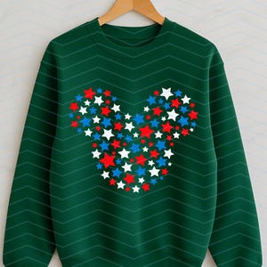 May include: A dark green long-sleeve sweatshirt featuring a subtle chevron pattern and a central graphic composed of numerous small red, white, and blue stars arranged to form the distinct silhouette of a mouse head with two round ears.