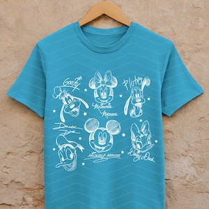May include: A turquoise t-shirt featuring a white sketch design of Disney characters, including Mickey Mouse, Minnie Mouse, Donald Duck, Daisy Duck, Goofy, and Pluto. The shirt has a crew neck and short sleeves.