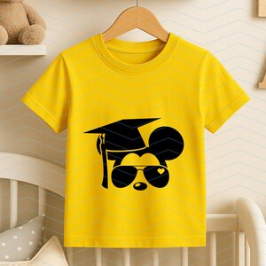 May include: Yellow t-shirt featuring a black graphic of a mouse wearing sunglasses and a graduation cap. The sunglasses have a heart shape on one lens. The shirt is hanging on a wooden hanger.
