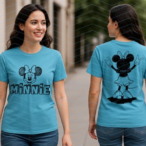 May include: A turquoise t-shirt with a black Minnie Mouse sketch on the front, and the name "MINNIE" below. The back displays a black silhouette of Minnie Mouse with raised arms. The shirt is made of a soft material.