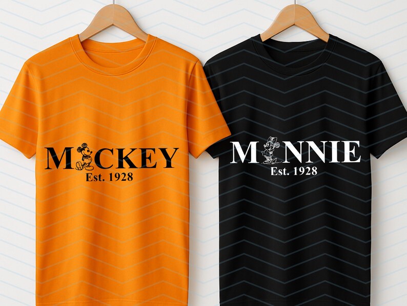 Pu&ograve; includere: Due magliette a maniche corte, una arancione e una nera, appese a grucce di legno. La maglietta arancione ha la scritta "Mickey" con un'immagine di un cartone animato e "Est. 1928". La maglietta nera ha "Minnie" con un'immagine di un cartone animato e "Est. 1928".
