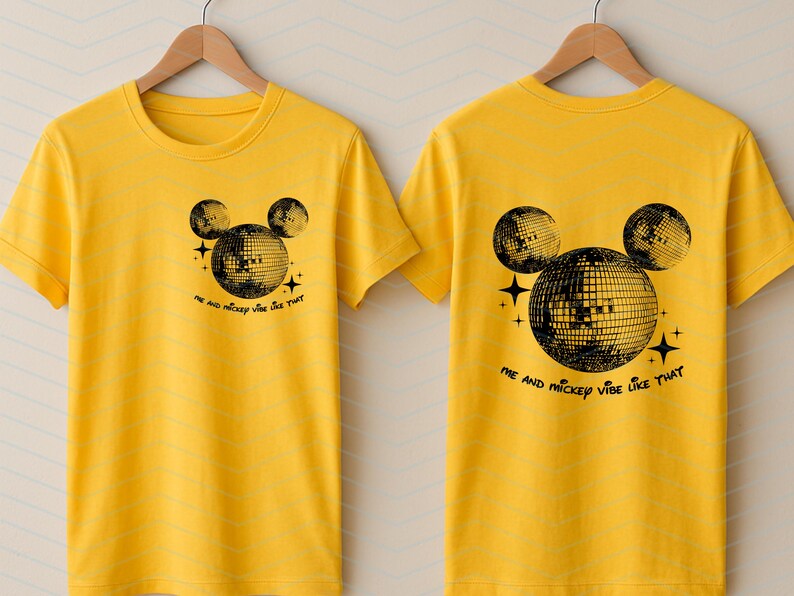 Puede incluir: Dos camisetas amarillas con una silueta negra de Mickey Mouse con orejas de bola de discoteca. El texto en las camisetas dice "Me and Mickey vibe like that."