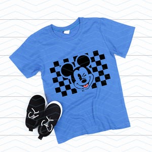 May include: A blue t-shirt with a black and white checkered pattern and a black and white cartoon image of Mickey Mouse winking with his tongue sticking out.