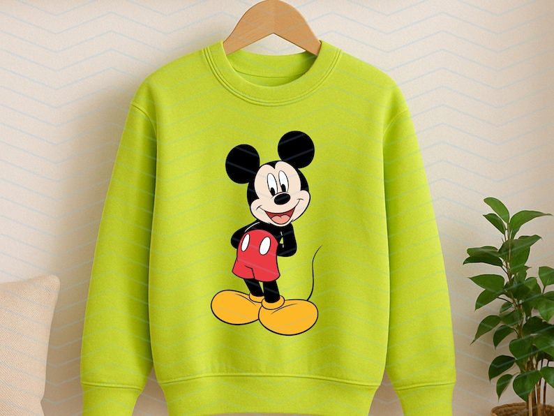 May include: A lime green long-sleeve sweatshirt featuring a centered graphic print of Mickey Mouse. The character is depicted with his signature black ears, red shorts, and large yellow shoes, standing against the solid bright green fabric.