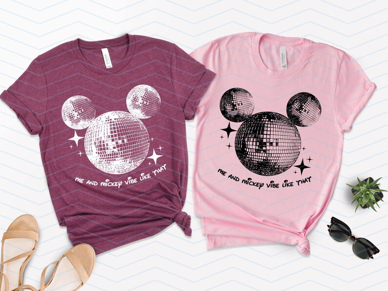 Puede incluir: Dos camisetas con un dise&ntilde;o de Mickey Mouse de bola de discoteca en blanco y negro. La camiseta granate dice "Me and Mickey vibe like that" y la camiseta rosa dice "Me and Mickey vibe like that".
