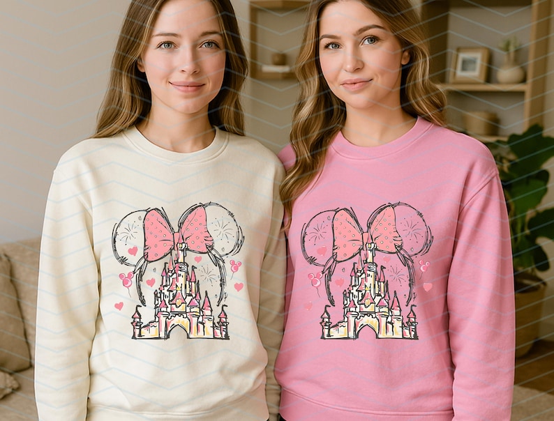Pu&ograve; includere: Due donne indossano felpe color crema e rosa con una grafica di un castello, un fiocco e palloncini. La grafica &egrave; un disegno stilizzato di un castello con un fiocco e palloncini su entrambi i lati.