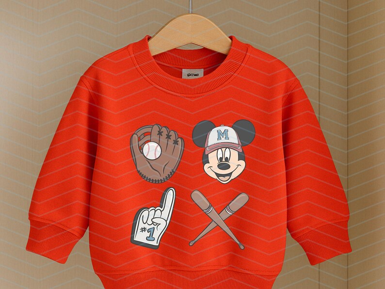 May include: Red sweatshirt with a Mickey Mouse graphic wearing a baseball cap with the letter "M" on it. The graphic also includes a baseball, a baseball glove, and two crossed baseball bats. The sweatshirt has a crew neck and long sleeves.
