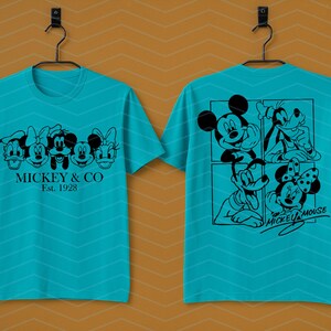 May include: A bright turquoise short-sleeve t-shirt featuring black line art graphics. The front displays five Disney character faces with the text MICKEY & CO EST. 1928. The back shows a four-panel grid of characters and the text MICKEY MOUSE.