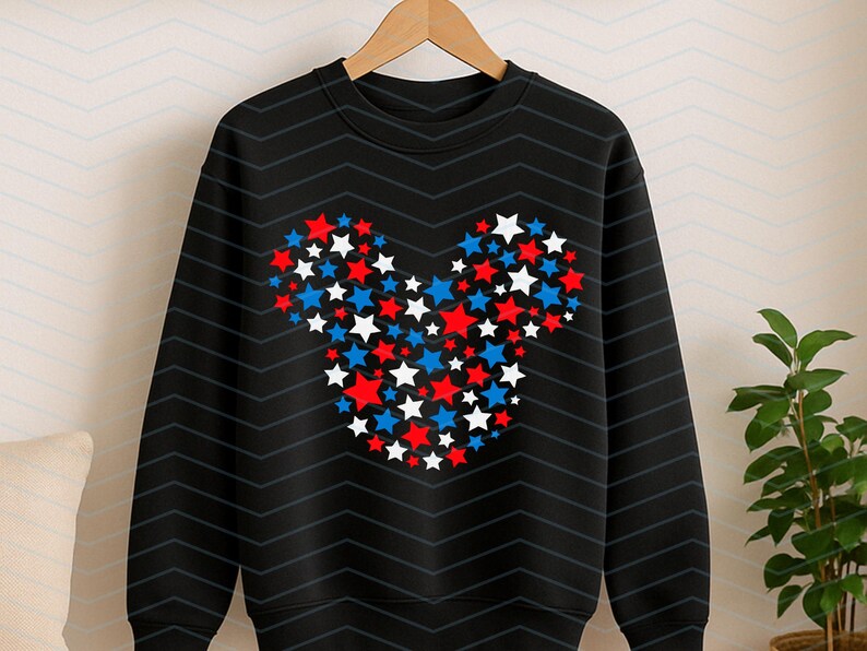 May include: A black long-sleeve sweatshirt featuring a central graphic composed of numerous small red, white, and blue stars arranged to form the distinct silhouette of a mouse head with two rounded ears and a circular face shape.
