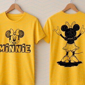 May include: Yellow t-shirt with a black and white Minnie Mouse design. The front shows Minnie's face and the name "MINNIE". The back features a silhouette of Minnie Mouse with her arms up. The t-shirt is hanging on a wooden hanger.
