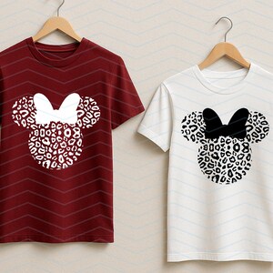 May include: Two short-sleeved t-shirts, one burgundy and one white, each featuring a Minnie Mouse design. The design includes a leopard print head and ears with a bow. The burgundy shirt has a white bow, while the white shirt has a black bow.