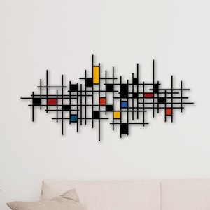 Può includere: Arte da parete in metallo nero con un design geometrico con linee intersecanti e quadrati colorati in rosso, giallo, blu e nero. L'opera d'arte è montata su una parete bianca sopra un divano beige.
