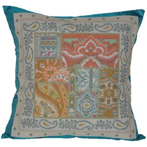 May include: A turquoise blue pillow with a white background and a colorful patchwork design. The design features a variety of geometric and floral patterns in shades of orange, pink, yellow, and blue.