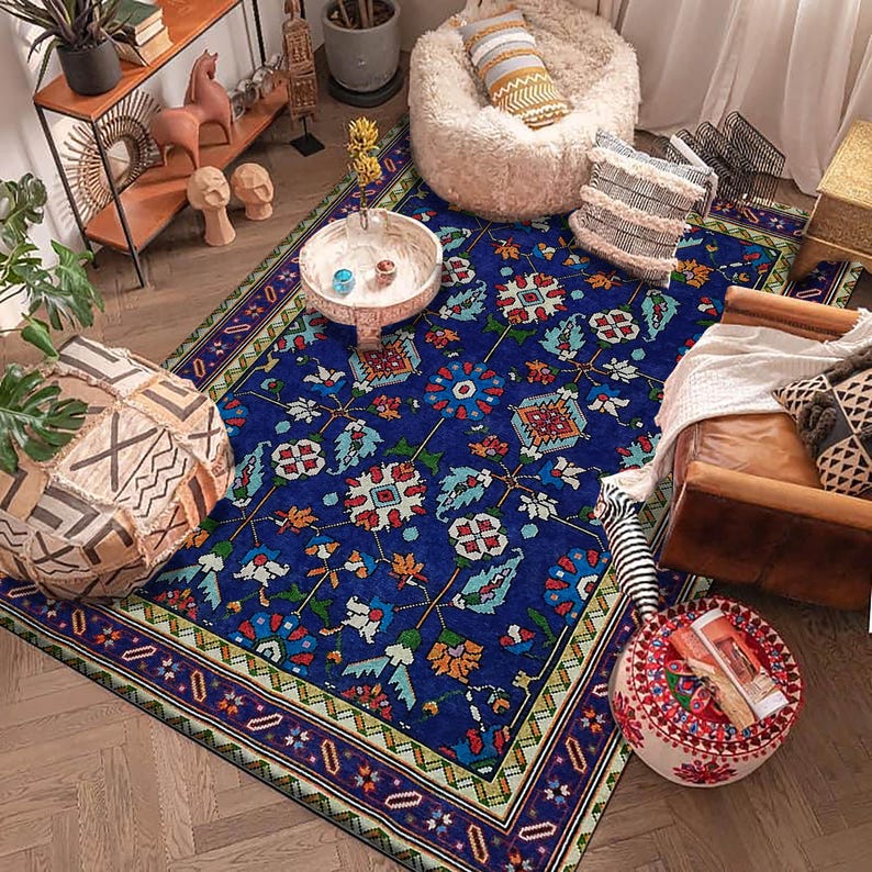 May include: A blue and green patterned rug with a floral design. The rug has a light yellow border with a dark blue and red trim. The rug is on a wooden floor and there are various decorative items in the background.