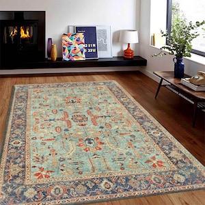May include: A teal blue area rug with a traditional Persian-style design featuring intricate floral patterns in shades of red, orange, and cream. The rug has a dark blue border with a cream and red accent.