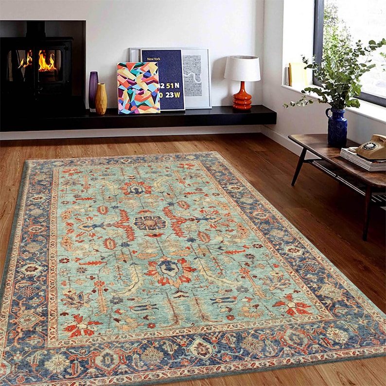 May include: A teal blue area rug with a traditional Persian-style design featuring intricate floral patterns in shades of red, orange, and cream. The rug has a dark blue border with a cream and red accent.