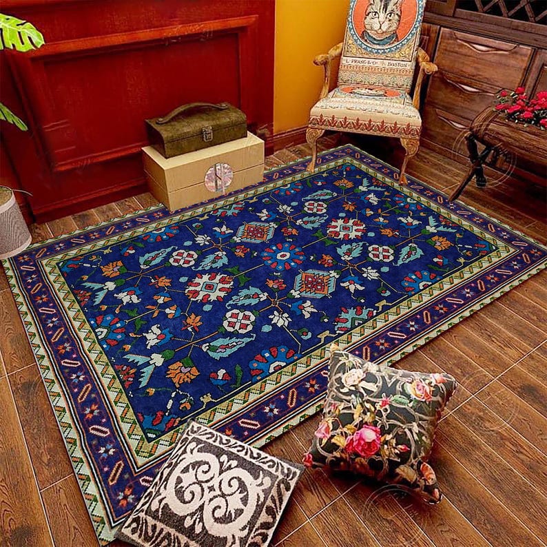 May include: A blue and green patterned rug with a floral design. The rug has a border with a light green, yellow, and red pattern. The rug is on a wooden floor with two decorative cushions.