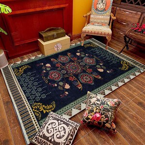 May include: A dark blue area rug with a floral pattern in shades of red, green, and yellow. The rug has a geometric border with a light blue background. The rug is on a wooden floor with two decorative cushions.