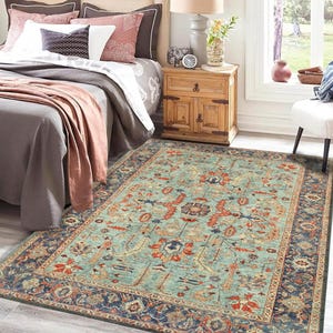 May include: A teal blue area rug with a traditional Persian design featuring intricate floral patterns in shades of red, orange, and cream. The rug has a dark blue border with a geometric pattern.