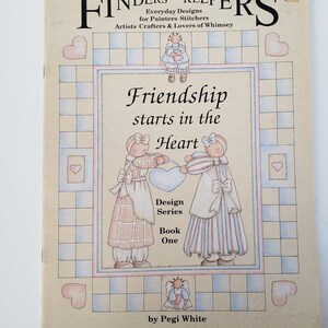 May include: A vintage book cover with the title "Friendship starts in the Heart." The cover features illustrations of two figures holding a heart, surrounded by hearts and a checkered border. The book is part of the "Design Series, Book One" by Pegi White.