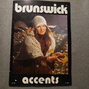May include: A vintage magazine cover with the word "brunswick" at the top. The cover features a woman wearing a white crocheted hat and shawl. The word "accents" is at the bottom. The background is a fall scene.