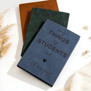 May include: Three notebooks in brown, green, and blue are stacked on a white surface. The blue notebook has the text "funny things my students said" and "So I'll never forget". The other notebooks have the word "funny" and "things" on them.