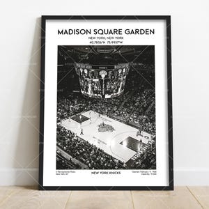 May include: Black and white framed print of Madison Square Garden in New York City. The image shows the basketball court with players, the scoreboard, and the audience. The text includes the name of the arena and the New York Knicks.
