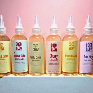 May include: Six bottles of Coco Glow refill cuticle oil with different flavour labels. The labels are in various colours, including yellow, blue, and pink, with the brand name in red. Each bottle contains 120ml of oil.