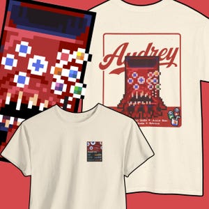 Può includere: T-shirt bianco sporco con grafica pixelata di un mostro rosso con il nome "Audrey". Il design include le parole "Soda, Juice Box, Soda, Advice". Una maglietta ha una piccola grafica quadrata del design.