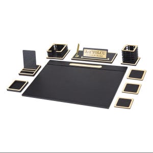 May include: A black and gold desk organizer set featuring a large rectangular desk pad, a nameplate with the text Arif YOLCU Lawyer & Avukat, a pen holder, a business card holder, a square note holder, and three square coasters.