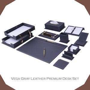 Puede incluir: Un juego de escritorio Vega Gray Leather Premium que incluye una bandeja para documentos de dos niveles, una caja rectangular para pañuelos, un portalápices, un soporte para notas, un tarjetero, un posavasos y un protector de escritorio.