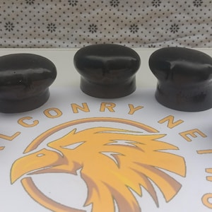 May include: Five black ceramic finials with a smooth, glossy finish. The finials are shaped like rounded domes with a slight indentation at the top. They are arranged in a row on a white surface.