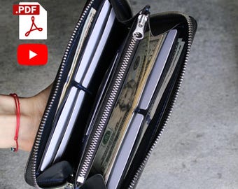 May include: Black leather zip-around wallet, open to reveal multiple card slots and a section filled with cash. The wallet has a silver zipper and a blue interior. The wallet is held open, displaying its contents.