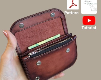 May include: Open brown leather wallet with a zippered compartment and snap closures. The wallet contains a small amount of cash. The image also includes icons for a PDF pattern and a tutorial.