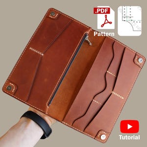 Könnte beinhalten: Offene braune Ledergeldbörse mit mehreren Taschen und einem Reißverschlussfach. Die Geldbörse hat weiße Nähte und Metall-Druckknöpfe. Das Bild enthält ein PDF-Symbol und das Wort "Pattern".