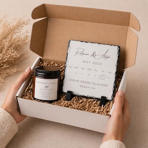 May include: A gift box containing a cinnamon vanilla candle and a slate calendar. The calendar displays "Rahman & Asiya" and the month of May 2026, with the text "AND WE CREATED YOU IN PAIRS" and "QURAN 78:8".