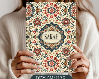 May include: A notebook with a cream-colored background and a detailed floral pattern in red, blue, and gold. The name "SARAH" is displayed in a central oval, and the word "PERSONALIZE" is at the bottom.