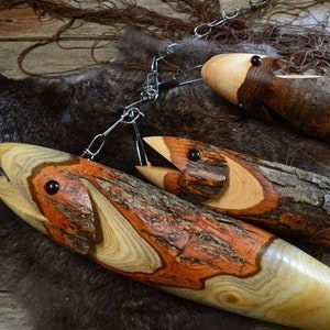 May include: Three wooden fish sculptures with intricate wood grain patterns and black eyes. The fish are hanging from a chain and are made from different types of wood.