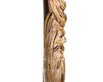 May include: A wooden walking stick with a carved face of a man with a beard. The stick is brown and has a natural wood finish.