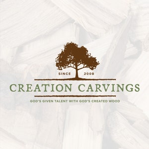 Może przedstawiać: Logo firmy zajmującej się rzeźbą w drewnie o nazwie "Creation Carvings". Logo przedstawia brązową sylwetkę drzewa z tekstem "Since 2008" poniżej. Tekst "Creation Carvings" jest zielony i znajduje się pod drzewem. Hasło "God's given talent with God's created wood" znajduje się pod nazwą firmy.