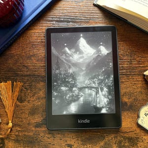 May include: A black and white image of a snowy mountain range with a city in the foreground. The image is displayed on a Kindle e-reader.