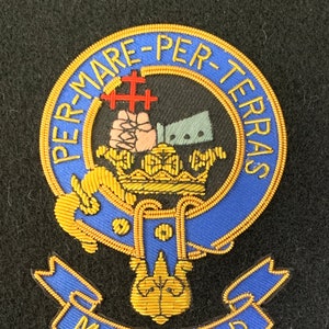 Può includere: Uno stemma ricamato in blu e oro con il testo "PER-MARE-PER-TERRAS" e "MACDONALD" su uno sfondo nero.