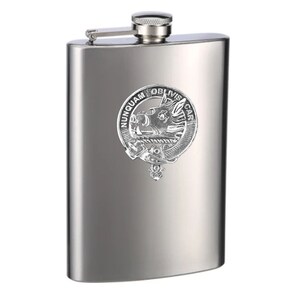 May include: A stainless steel hip flask with a silver-coloured crest featuring a boar's head and the text "NUNQUAM OBLIVISCAR".