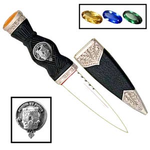 May include: A black and silver Scottish dirk with a silver crest featuring a castle and the text "Fortis et Fidelis". The dirk has a black leather scabbard with silver accents. The dirk is displayed with a yellow, blue, and green gemstone.