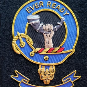 May include: A blue and gold embroidered crest with the text "EVER READY" and "BURNS" on a black background. The crest features a raised fist holding a horn.