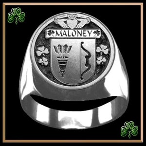 May include: A silver ring with a crest featuring the name "MALONEY" and a design of an arrow and bow. The crest is surrounded by shamrocks.