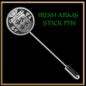 May include: Silver stick pin with a round, silver, embossed design featuring a coat of arms with the text "Clancy" and shamrocks. The text "Irish Arms Stick Pin" is written in green letters on a black background.